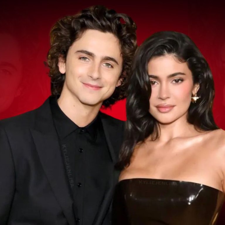 Kylie Jenner and Timothée Chalamet pose together in elegant black outfits against a striking red backdrop.